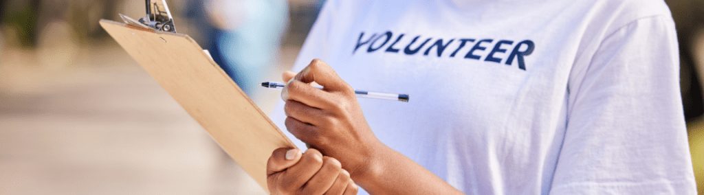 Closeup of a woman holding a clipboard with a volunteer shirt on