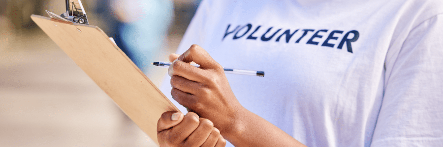 Closeup of a woman holding a clipboard with a volunteer shirt on