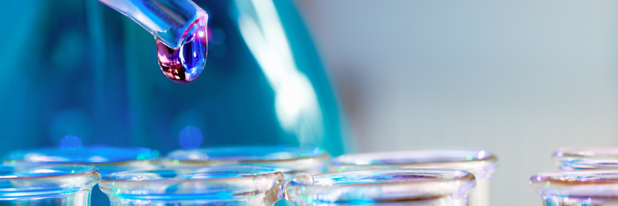 Close up of liquid in a dropper above test tubes